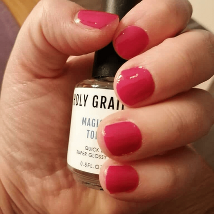 Hand holding nail care product wearing vibrant pink nail wraps manicure