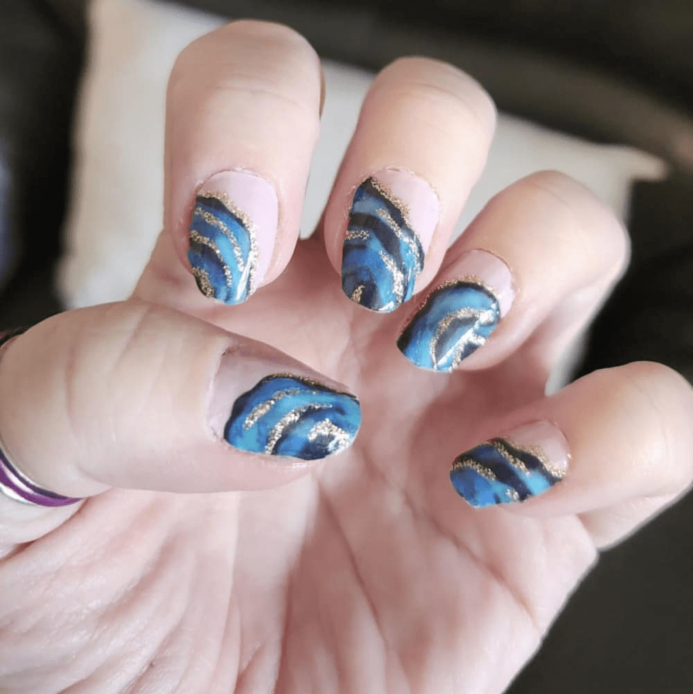 Metallic blue swirl nail art wraps on cupped hand displaying shimmery vortex pattern