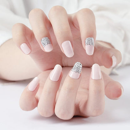 Hands displaying pink nail wraps with black polka dot accent nails manicure