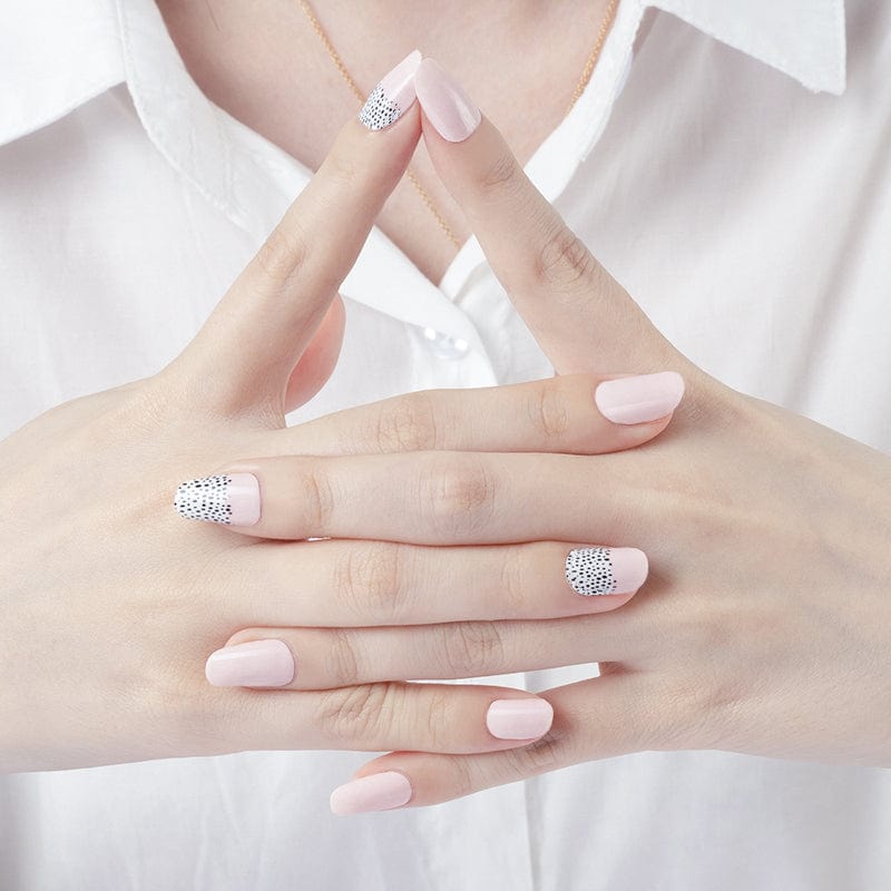 Clasped hands showing pink nail wraps with black polka dot nail art design