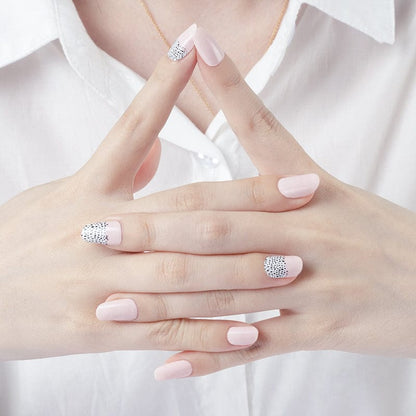 Clasped hands showing pink nail wraps with black polka dot nail art design