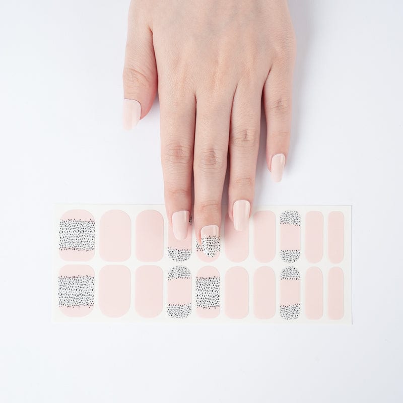 Hand with pink nail wraps beside wide fit polka dot nail wrap sheet