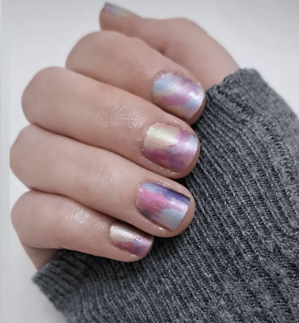 Multicolour watercolour nail wraps on hand displaying soft pastel gradient nail art