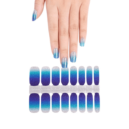 Hand displaying blue ombre nail wraps with matching nail wrap sheet below