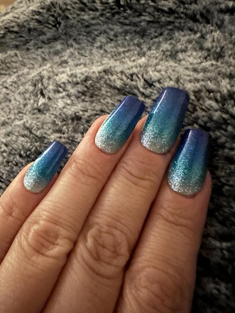 Blue to silver gradient nail art with shimmer finish on hand
