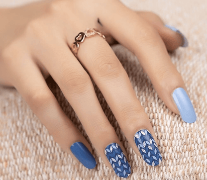 Hand wearing blue geometric wave pattern nail wraps with coastal chevron nail art design