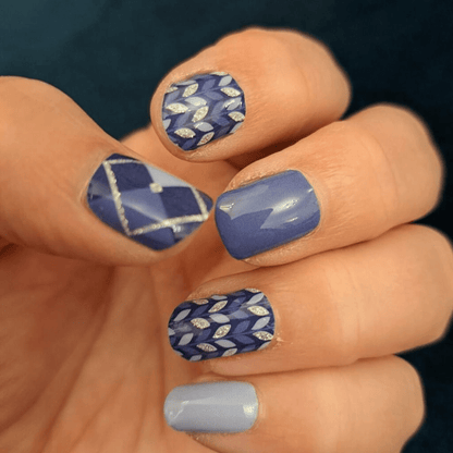 Blue wave pattern nail wraps on hand featuring mixed geometric designs and solid colours