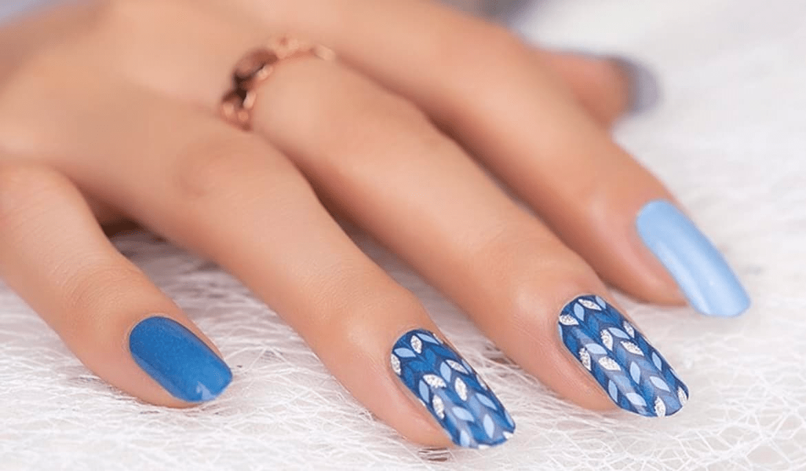 Blue wavy pattern non-UV nail wraps on hand showing geometric wave design