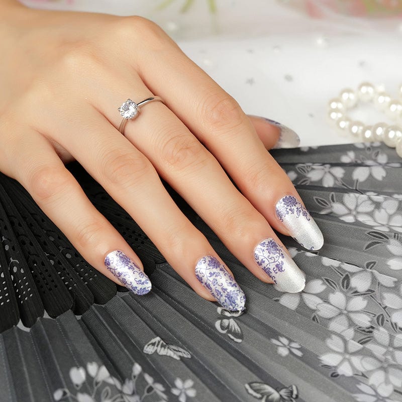 Elegant blue porcelain pattern nail wraps on hand with diamond ring and pearls