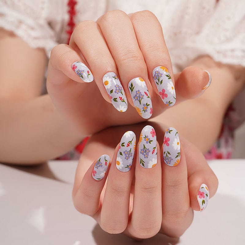 Both hands displaying colorful wildflower nail wraps with romantic botanical print design
