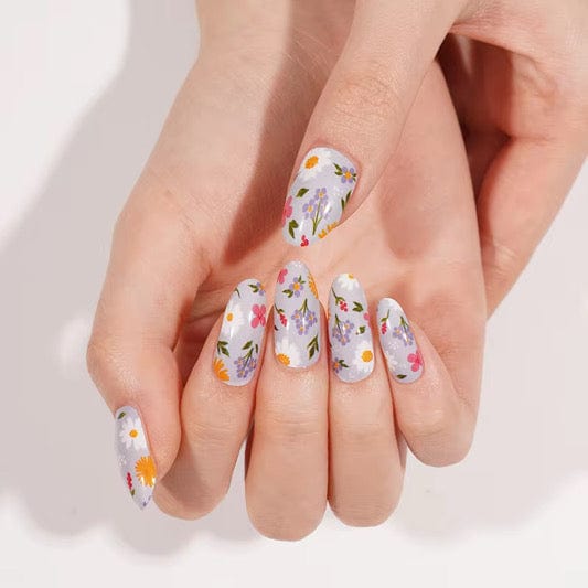 Hands showing botanical nail wraps featuring white base with colourful daisy floral design