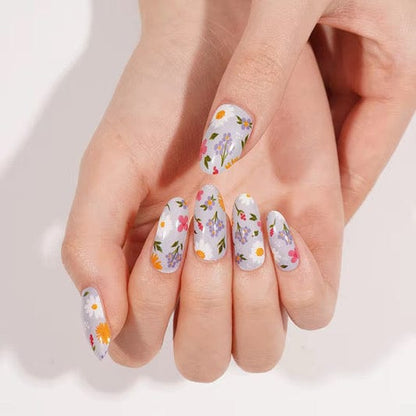 Hands showing botanical nail wraps featuring white base with colourful daisy floral design