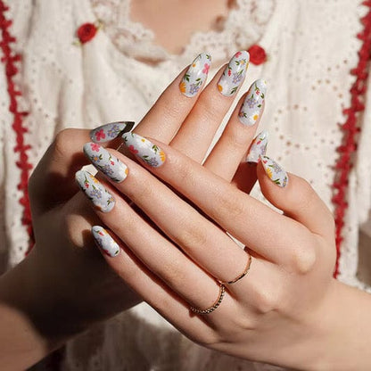 Floral nail wraps on hand showing multicoloured wildflower pattern with daisies for at-home manicure
