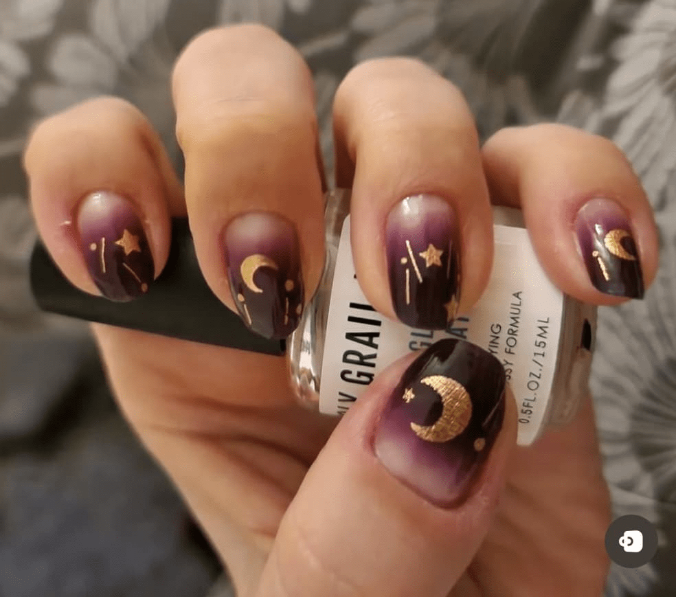 Mystical purple ombre nail wraps with gold moon and star designs on hand