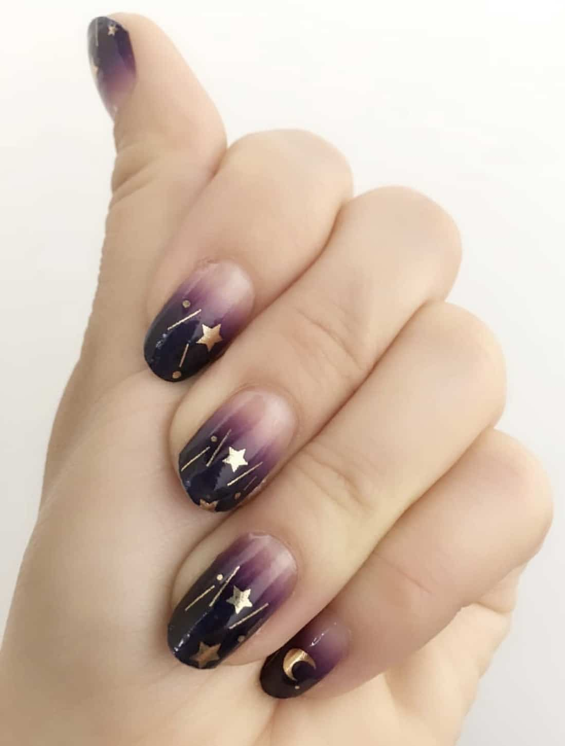Purple ombre nail wraps with gold celestial stars and moons on hand