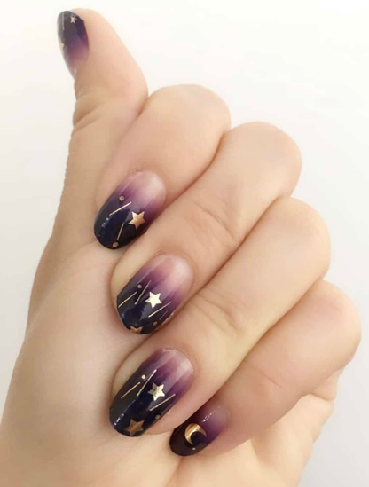 Purple ombre nail wraps with gold celestial stars and moons on hand