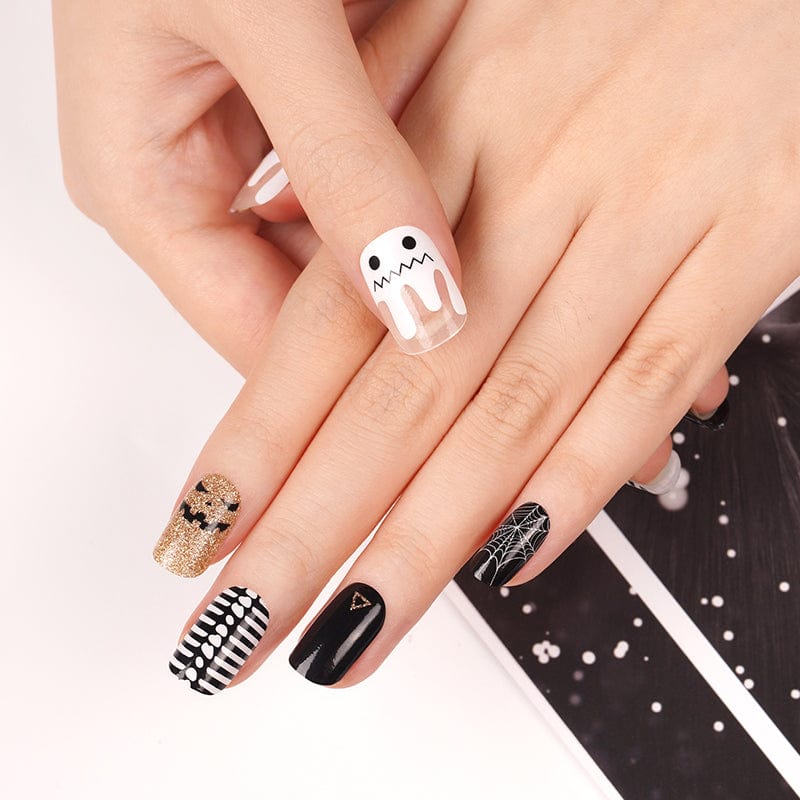 Halloween nail wraps on hand featuring ghost, black glitter, copper, and striped designs
