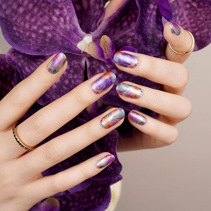 Chrome mirror nail wraps on hand with purple orchid showing holographic finish