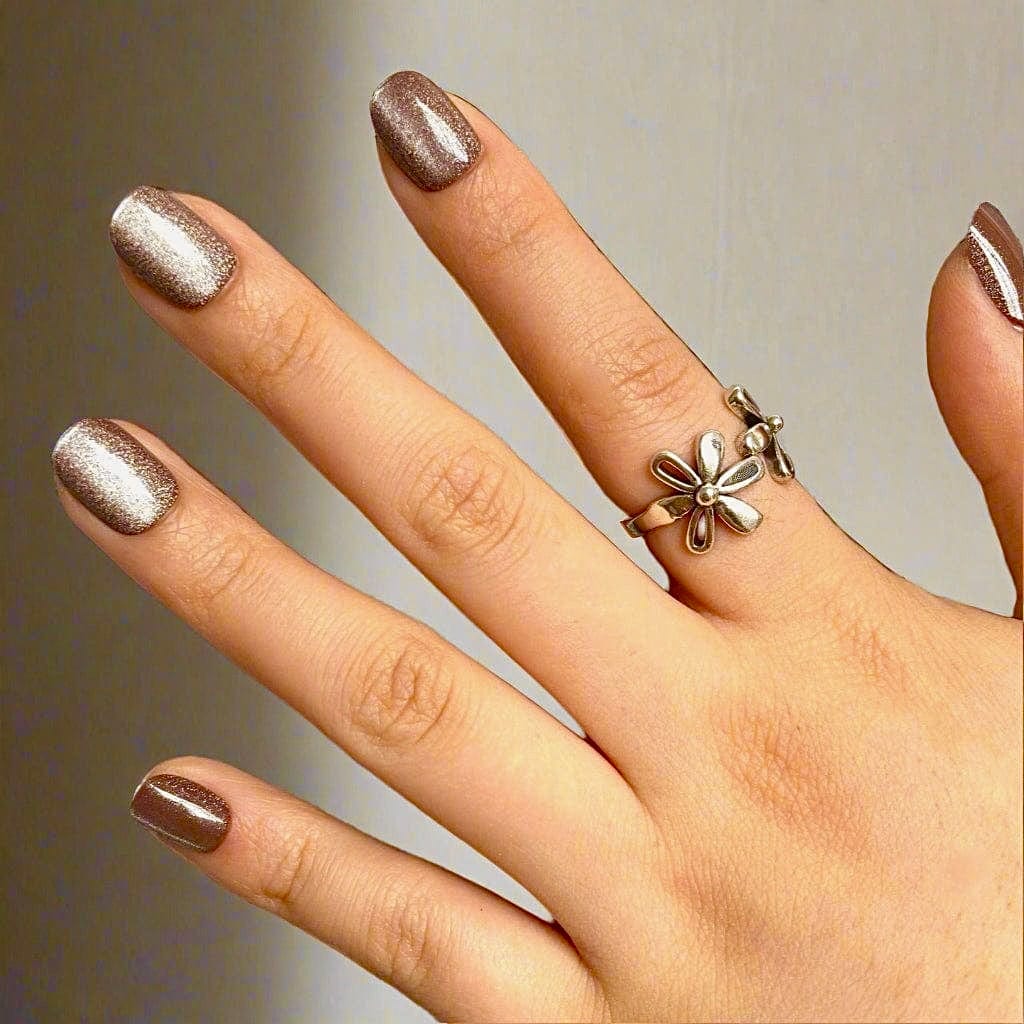 Rose gold cat's eye press-on nails on hand with gold flower ring showing nail art