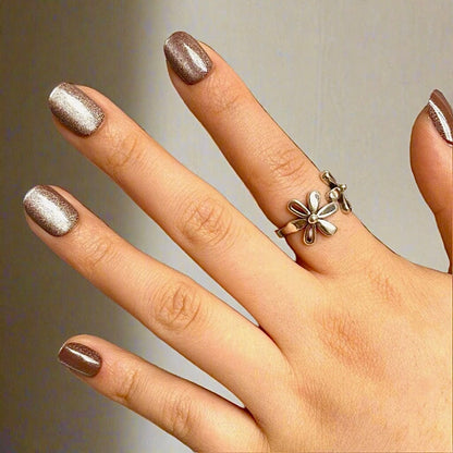 Rose gold cat's eye press-on nails on hand with gold flower ring showing nail art