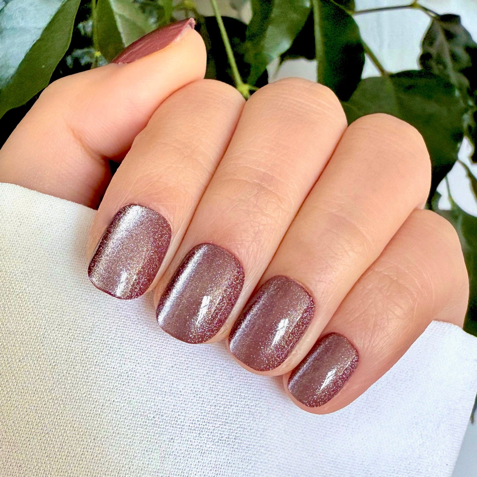 Mauve cat's eye gel press-on nails with glossy shimmer finish on natural hand