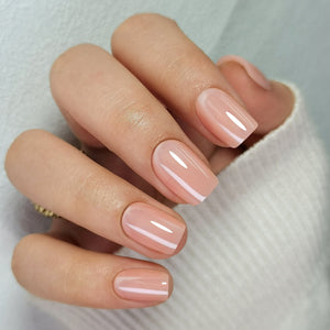 Glossy nude pink press-on nails in short square shape on hand showing glazed finish