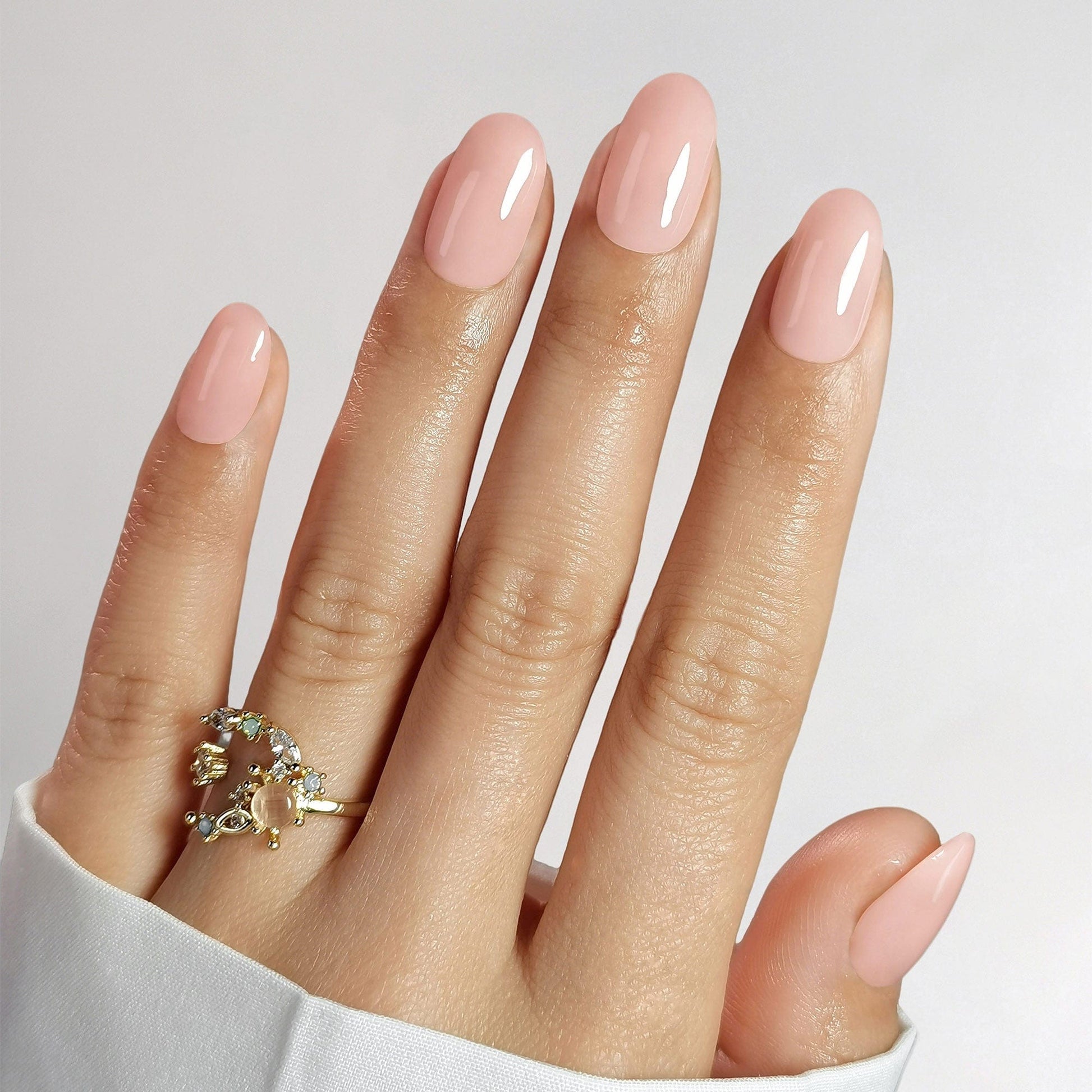Short oval nude pink gel press-on nails on hand showing natural glossy finish