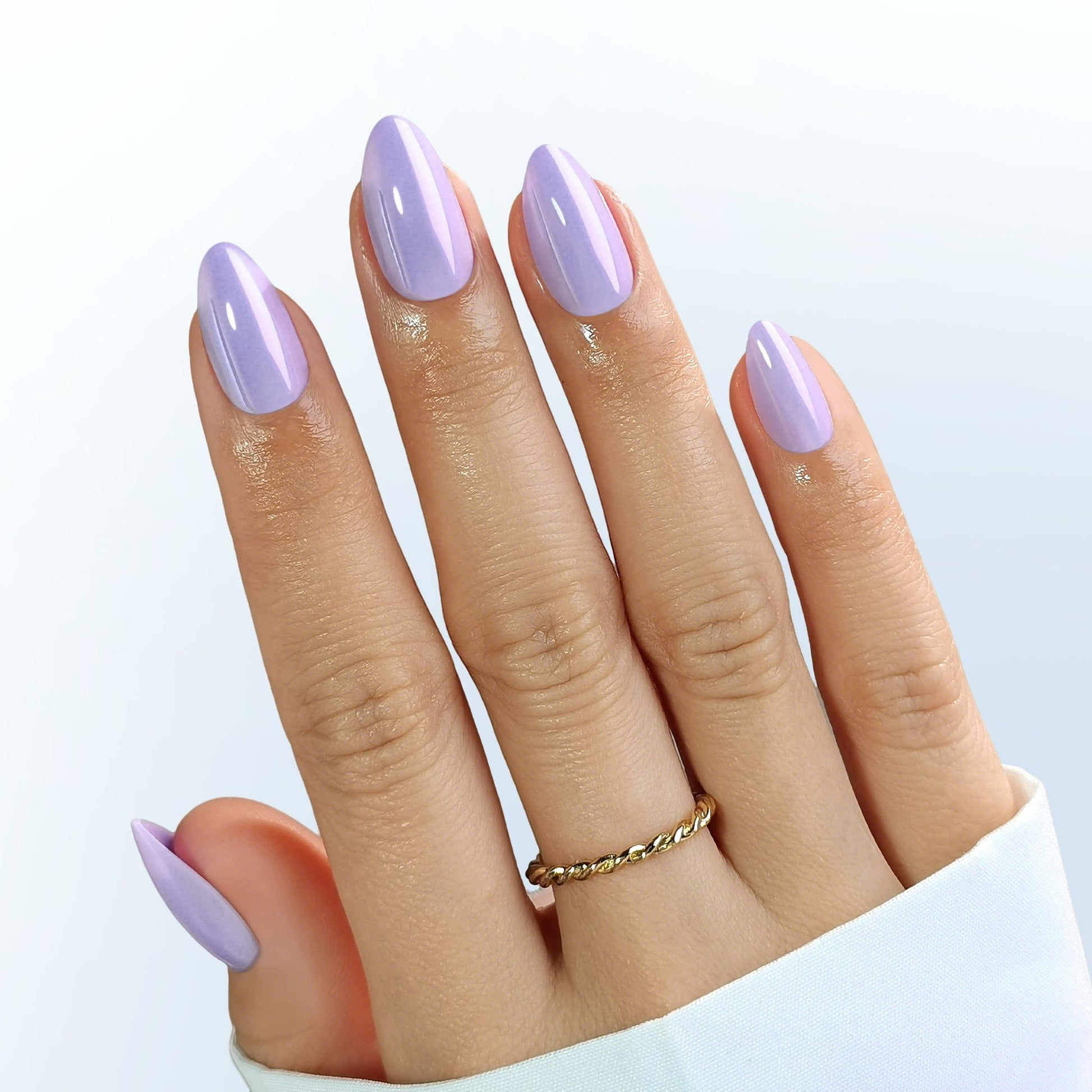 Short almond press-on nails in glossy lilac purple shade on hand with ring