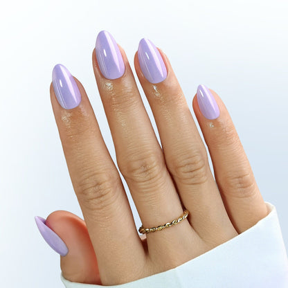 Short almond press-on nails in glossy lilac purple shade on hand with ring
