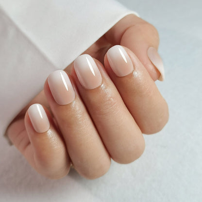 Nude glossy press-on nails on hand in natural oval shape for everyday manicure
