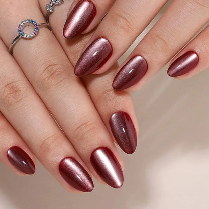 Deep red cat's eye press-on nails with copper shimmer in short almond shape