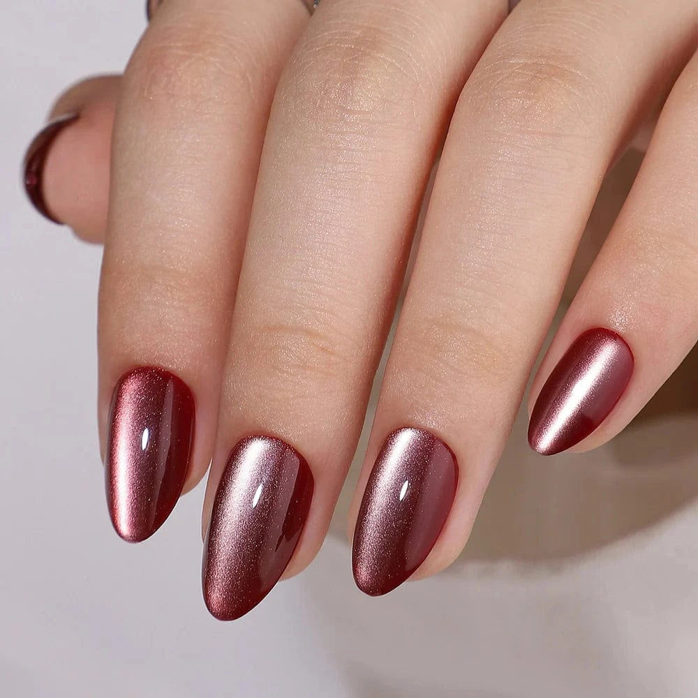 Burgundy cat's eye press-on nails in short almond shape on hand with magnetic shimmer finish
