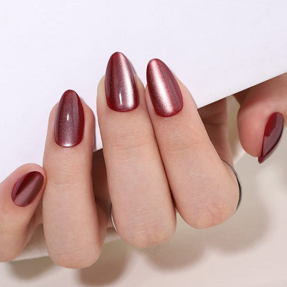 Deep burgundy cat's eye press-on nails with magnetic shimmer effect on hand