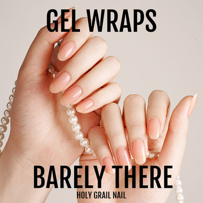 Hands wearing nude gel nail wraps showing natural barely there manicure with pearl bracelet