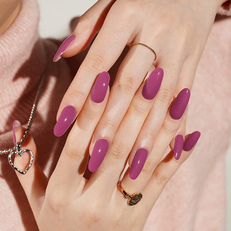 Berry purple gel nail wraps on hand showing glossy oval shaped manicure