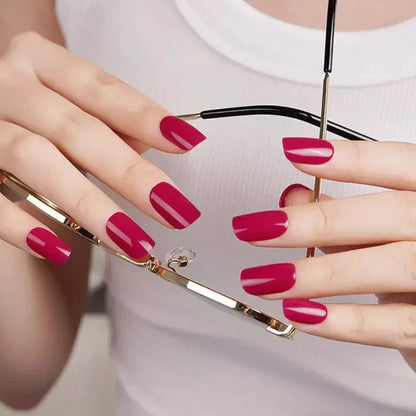 Bordeaux red gel nail wraps on hands holding gold compact mirror for glossy manicure look