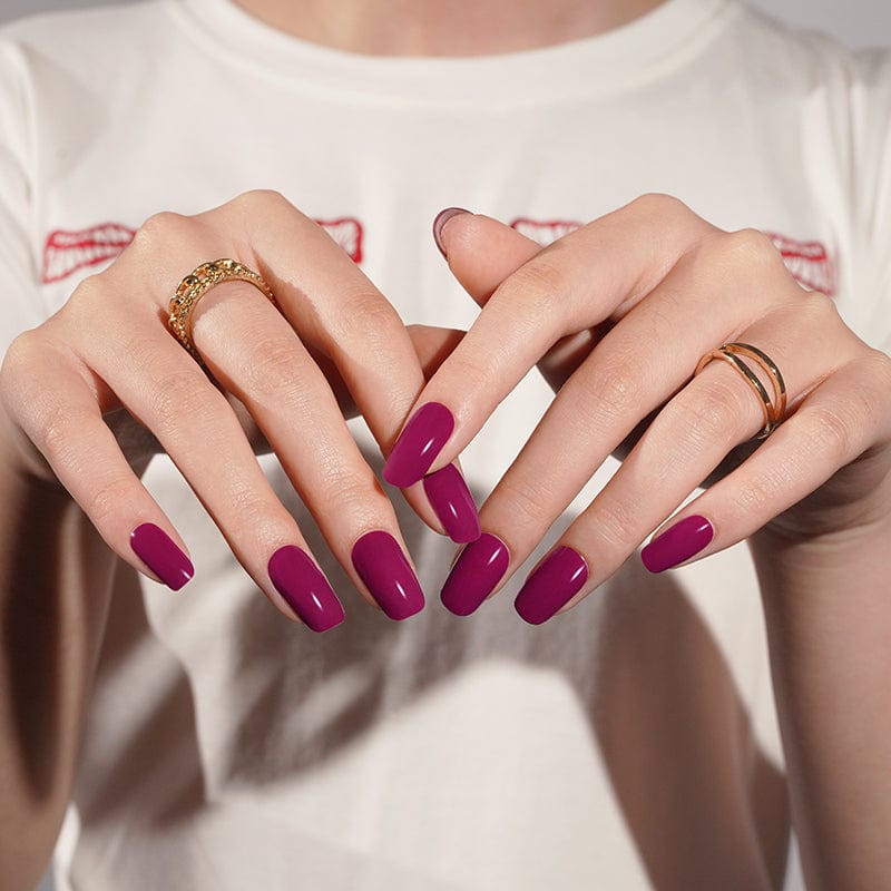 Claret burgundy gel nail wraps manicure on hands with gold rings