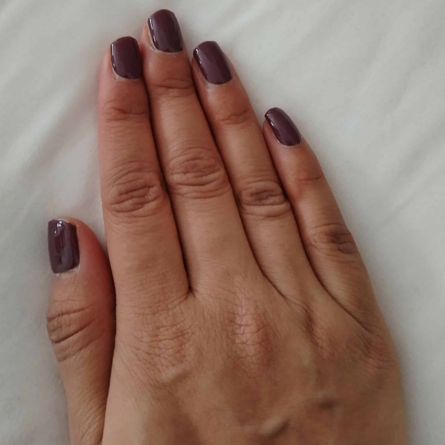 Hands showing deep grape burgundy gel nail wraps with glossy wine finish manicure
