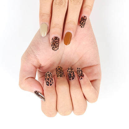 Hands displaying brown leopard print gel nail wraps with spotted animal design