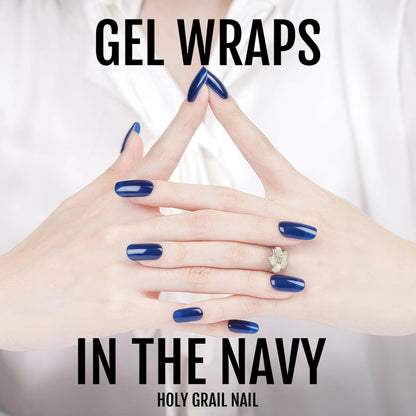Navy gel nail wraps on interlaced hands displaying elegant glossy blue nails