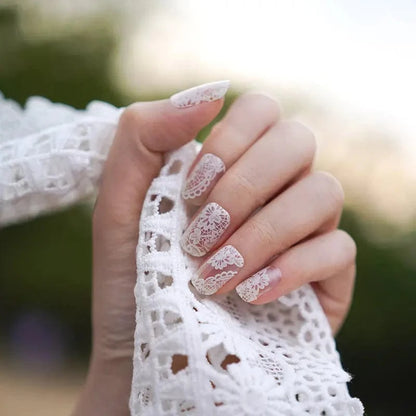 Hand wearing white lace gel nails with intricate vintage pattern for wedding manicure