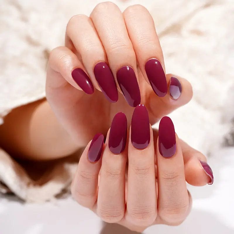 Deep burgundy glossy gel nail wraps on hands showing rich wine red manicure
