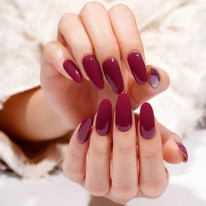 Deep burgundy glossy gel nail wraps on hands showing rich wine red manicure