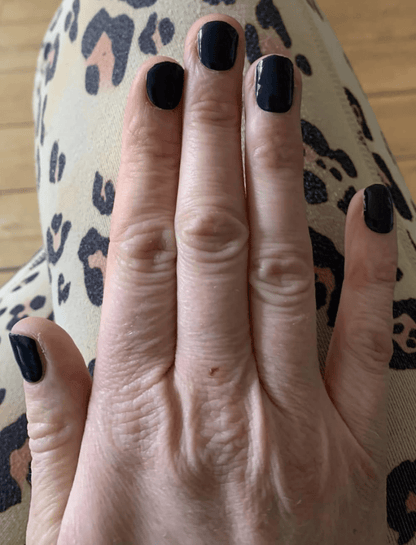 Black glossy gel nail wraps on hand showing midnight solid colour manicure