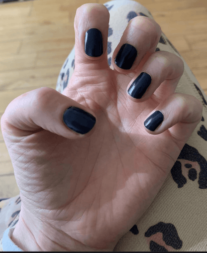 Hand displaying black gel nail wraps in midnight shade with glossy finish