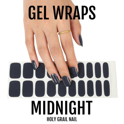 Hand displaying black gel nail wraps with matching wrap sheet showing midnight manicure design