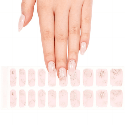 Hand wearing pink nude gel nail wraps featuring rose gold celestial fortune tarot designs