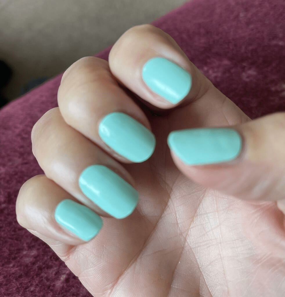 Turquoise blue gel nail wraps on hand showing glossy finish manicure