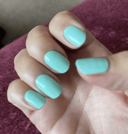 Turquoise blue gel nail wraps on hand showing glossy finish manicure