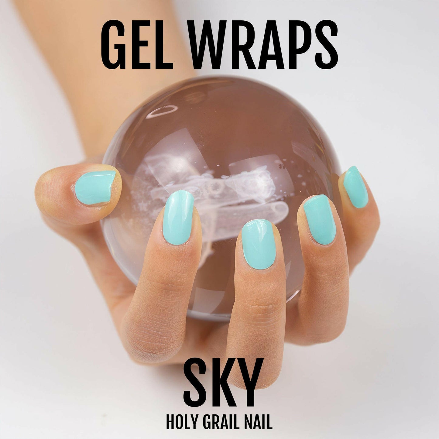 Hands with turquoise gel nail wraps holding crystal ball showing glossy manicure finish
